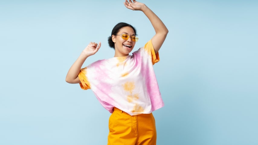 A woman wearing a colorful AOP tie-dyed t-shirt.