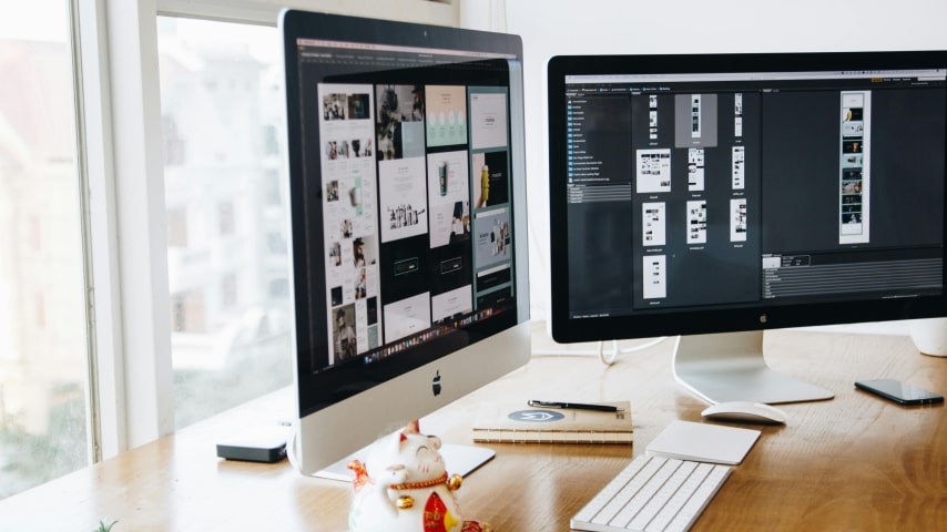 A set of two monitors displaying branding elements in design.