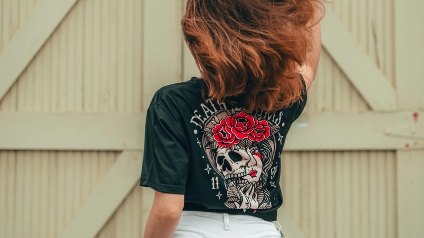 A woman wearing a dark custom t-shirt with a back print.
