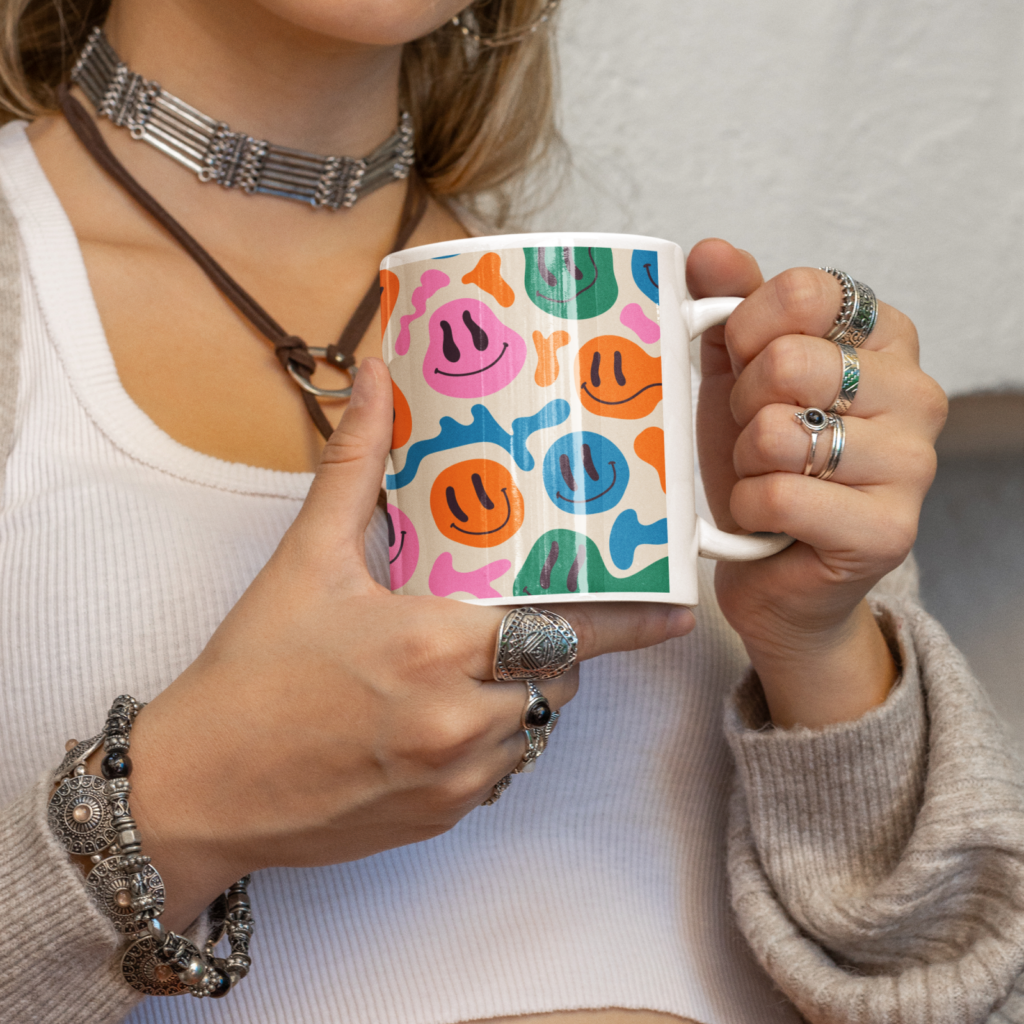 A woman holding a mug with a custom illustrated smiling faces print.