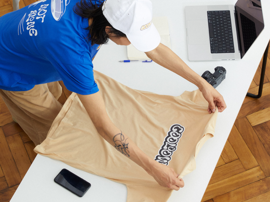 A person checking out a custom beige t-shirt made with print-on-demand.