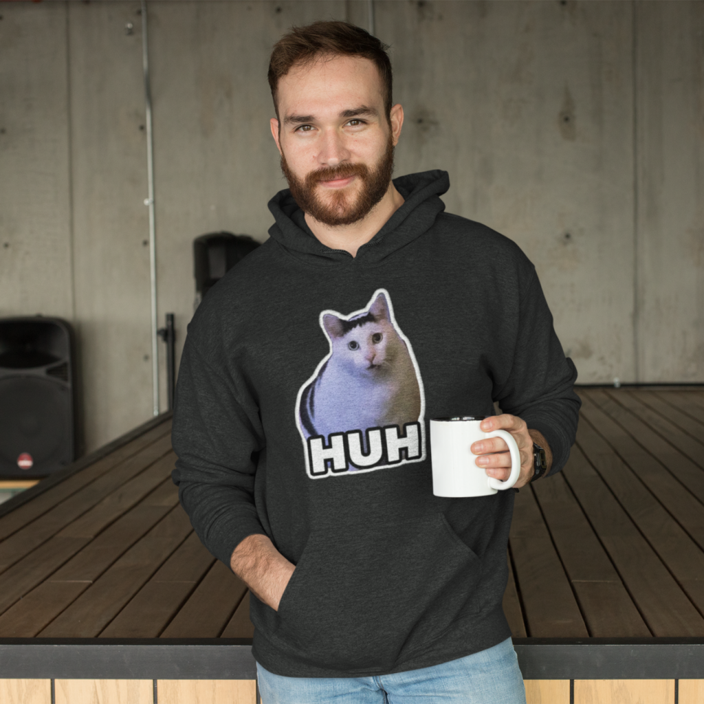 A man wearing a trending hoodie with a cat meme print saying “Huh”.