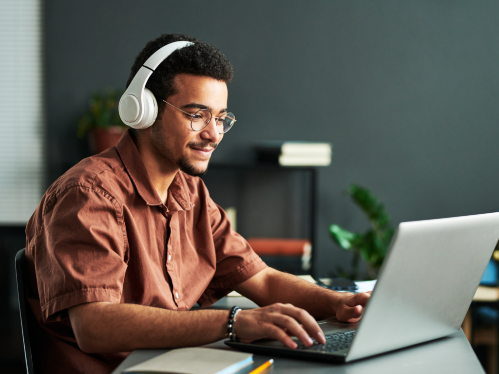 Man in headphones works on his laptop, researching WooCommerce SEO strategies.